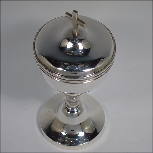 An Antique Edwardian Sterling Silver Ciborium, having a plain round body with reeded borders and gold-gilt interior, sitting on a matching pedestal foot with central baluster, and a lift-off lid with cruciform finial. Made by Henry Lambert of London in 1902. The dimensions of this fine hand-made antique silver ciborium are height 19 cms (7.5 inches), diameter of cup 8.5 cms (3.3 inches), and it weighs a total of approx. 264g (8.5 troy ounces).