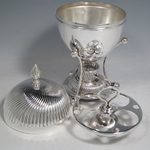 Antique Edwardian silver-plated egg coddler, having a plain round body, with lift-off lid having swirl fluting and a flame finial, and internal holder for four eggs, attached to a frame and stand with an original burner, all sitting on three ball feet. Made by Welbeck & Co., in ca. 1900. The dimensions of this fine hand-made silver plated egg coddler are height 23.5 cms (9.25 inches), and diameter 11 cms (4.3 inches).