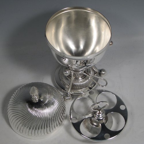 Antique Edwardian silver-plated egg coddler, having a plain round body, with lift-off lid having swirl fluting and a flame finial, and internal holder for four eggs, attached to a frame and stand with an original burner, all sitting on three ball feet. Made by Welbeck & Co., in ca. 1900. The dimensions of this fine hand-made silver plated egg coddler are height 23.5 cms (9.25 inches), and diameter 11 cms (4.3 inches).