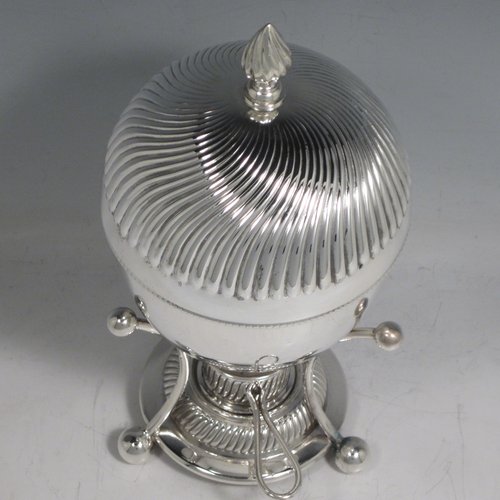Antique Edwardian silver-plated egg coddler, having a plain round body, with lift-off lid having swirl fluting and a flame finial, and internal holder for four eggs, attached to a frame and stand with an original burner, all sitting on three ball feet. Made by Welbeck & Co., in ca. 1900. The dimensions of this fine hand-made silver plated egg coddler are height 23.5 cms (9.25 inches), and diameter 11 cms (4.3 inches).