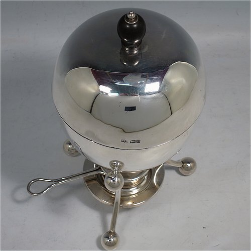 A rare Antique Edwardian Sterling Silver egg coddler, having a plain round body, with lift-off lid and wooden finial, sitting in a wire-work frame with ball terminals, an interior egg-holder for four eggs, and an original burner, all sitting on four ball feet. Made by Mappin & Webb of Sheffield in 1907. The dimensions of this fine hand-made antique silver egg coddler are height 23 cms (9 inches), diameter 11 cms (4.3 inches), and it weighs approx. 510g (16.5 troy ounces).