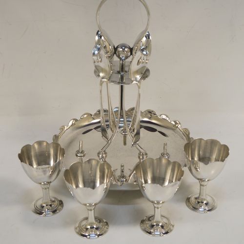A pretty Sterling Silver egg cruet set, having a plain round body with a scalloped border, four plain round egg cups, a loop handle and holder with four original egg spoons, and all sitting on four ball feet. This elegant silver egg cruet set was all made by John Batt of Sheffield in 1924. The dimensions of this fine hand-made silver egg cruet set are height 18.5 cms (7.25 inches), diameter of main body 14.5 cms (5.75 inches), with a total weight of approx. 543g (17.5 troy ounces).