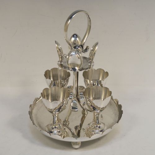 A pretty Sterling Silver egg cruet set, having a plain round body with a scalloped border, four plain round egg cups, a loop handle and holder with four original egg spoons, and all sitting on four ball feet. This elegant silver egg cruet set was all made by John Batt of Sheffield in 1924. The dimensions of this fine hand-made silver egg cruet set are height 18.5 cms (7.25 inches), diameter of main body 14.5 cms (5.75 inches), with a total weight of approx. 543g (17.5 troy ounces).