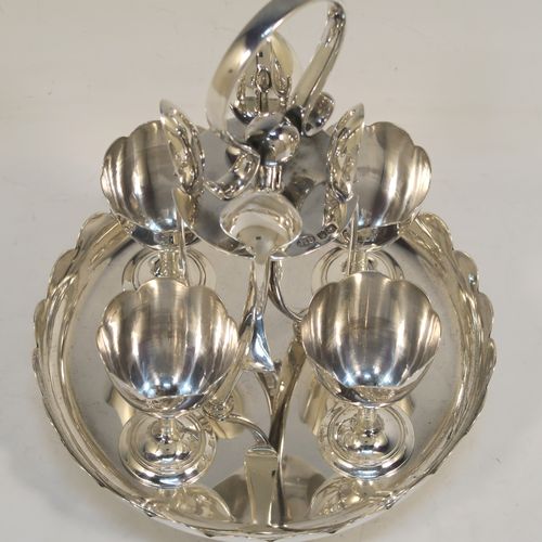 A pretty Sterling Silver egg cruet set, having a plain round body with a scalloped border, four plain round egg cups, a loop handle and holder with four original egg spoons, and all sitting on four ball feet. This elegant silver egg cruet set was all made by John Batt of Sheffield in 1924. The dimensions of this fine hand-made silver egg cruet set are height 18.5 cms (7.25 inches), diameter of main body 14.5 cms (5.75 inches), with a total weight of approx. 543g (17.5 troy ounces).