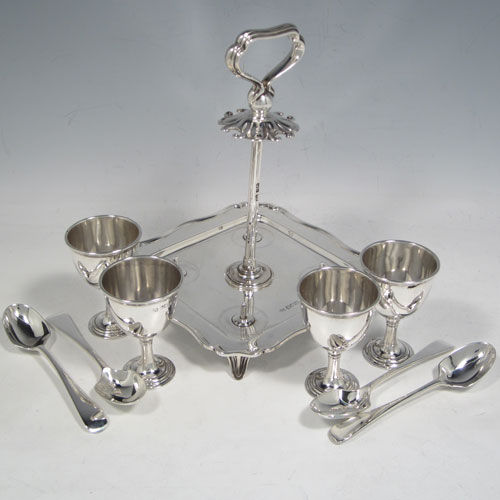 Antique Edwardian sterling silver egg cruet set, having four plain round egg cups sitting on pedestal feet, four plain egg spoons, and a cast loop handle attached to a square base with shaped reeded border sitting on four flange feet. Made by Henry Atkins of Sheffield in 1902. The spoons are made by Jackson & Fullerton of London in 1902. The dimensions of this fine hand-made silver egg cruet set are height 18 cms (7 inches), the base is 14 cms (5.5 inches) square and the total weight is approx. 647g (21 troy ounces).