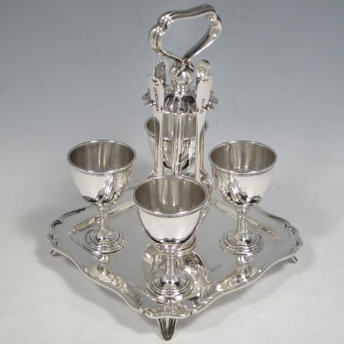 Antique Edwardian sterling silver egg cruet set, having four plain round egg cups sitting on pedestal feet, four plain egg spoons, and a cast loop handle attached to a square base with shaped reeded border sitting on four flange feet. Made by Henry Atkins of Sheffield in 1902. The spoons are made by Jackson & Fullerton of London in 1902. The dimensions of this fine hand-made silver egg cruet set are height 18 cms (7 inches), the base is 14 cms (5.5 inches) square and the total weight is approx. 647g (21 troy ounces).