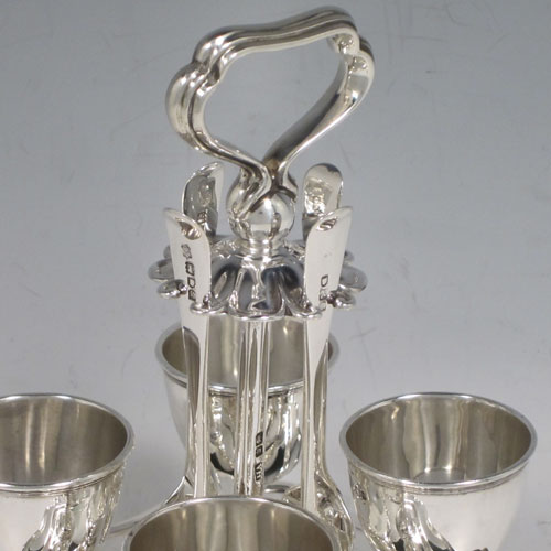 Antique Edwardian sterling silver egg cruet set, having four plain round egg cups sitting on pedestal feet, four plain egg spoons, and a cast loop handle attached to a square base with shaped reeded border sitting on four flange feet. Made by Henry Atkins of Sheffield in 1902. The spoons are made by Jackson & Fullerton of London in 1902. The dimensions of this fine hand-made silver egg cruet set are height 18 cms (7 inches), the base is 14 cms (5.5 inches) square and the total weight is approx. 647g (21 troy ounces).