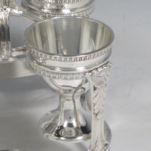 Sterling silver egg cruet set, having four round egg cups, sitting inside a frame with gadroon, shell, and anthemion leaf decoration, and a reeded loop handle, all sitting on four flange feet. Made by George Hancock of Sheffield in 1915. Please note that there are no spoons with this stand. The dimensions of this fine hand-made silver egg cruet set are height 16 cms (6.25 inches), the base is 11 cms (4.3 inches) square and the total weight is approx. 483g (15.6 troy ounces).