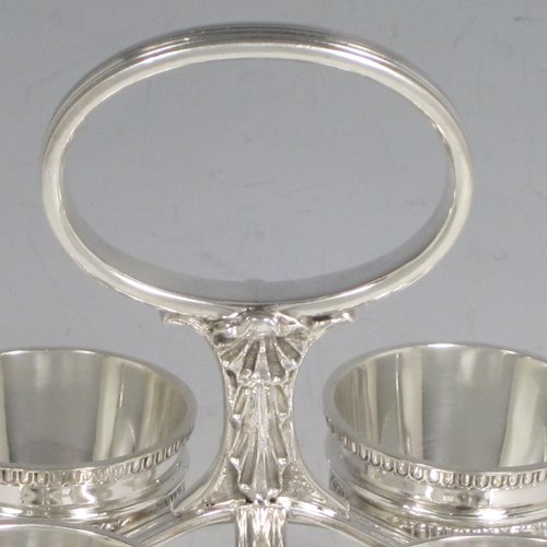 Sterling silver egg cruet set, having four round egg cups, sitting inside a frame with gadroon, shell, and anthemion leaf decoration, and a reeded loop handle, all sitting on four flange feet. Made by George Hancock of Sheffield in 1915. Please note that there are no spoons with this stand. The dimensions of this fine hand-made silver egg cruet set are height 16 cms (6.25 inches), the base is 11 cms (4.3 inches) square and the total weight is approx. 483g (15.6 troy ounces).