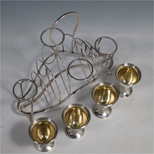 An Antique Georgian Sterling Silver egg cruet set, having four removable plain round egg cups with reeded borders and gold-gilt interiors, and all sitting in a wire-work frame toast-rack stand with four flange feet, and a looped carrying handle. Made by William Abdy of London in 1801. The dimensions of this fine hand-made antique silver egg cruet and toast set are height 22 cms (8.75 inches), length 23 cms (9 inches), width 14 cms (5.5 inches), with a total weight of approx. 500g (16 troy ounces).