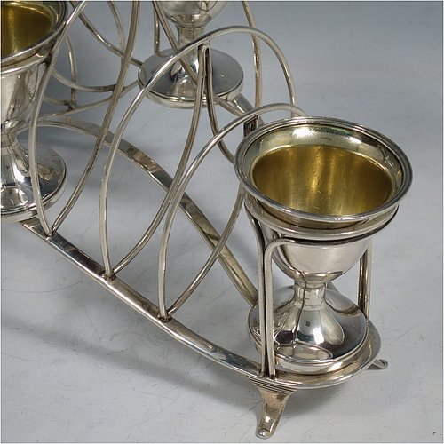 An Antique Georgian Sterling Silver egg cruet set, having four removable plain round egg cups with reeded borders and gold-gilt interiors, and all sitting in a wire-work frame toast-rack stand with four flange feet, and a looped carrying handle. Made by William Abdy of London in 1801. The dimensions of this fine hand-made antique silver egg cruet and toast set are height 22 cms (8.75 inches), length 23 cms (9 inches), width 14 cms (5.5 inches), with a total weight of approx. 500g (16 troy ounces).