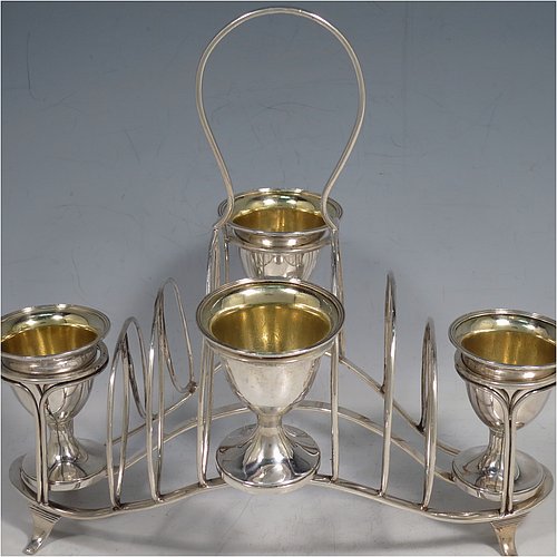 An Antique Georgian Sterling Silver egg cruet set, having four removable plain round egg cups with reeded borders and gold-gilt interiors, and all sitting in a wire-work frame toast-rack stand with four flange feet, and a looped carrying handle. Made by William Abdy of London in 1801. The dimensions of this fine hand-made antique silver egg cruet and toast set are height 22 cms (8.75 inches), length 23 cms (9 inches), width 14 cms (5.5 inches), with a total weight of approx. 500g (16 troy ounces).