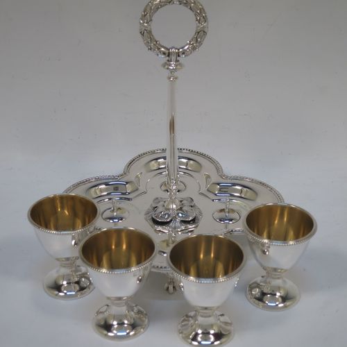 A very pretty Antique Victorian Sterling Silver egg cruet set, having four plain round egg cups with bead borders and gold-gild interiors sitting on pedestal feet, together with a cast laurel leaf loop handle attached to a lobed base with an applied bead-edged border, and all sitting on four cast claw and ball feet. Made by Elkington and Co., of Birmingham in 1866. The dimensions of this fine hand-made antique silver egg cruet set are height 18 cms (7 inches), width of base is 16.5 cms (6.5 inches), and the total weight is approx. 500g (16 troy ounces).