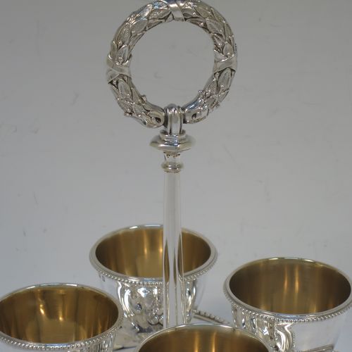 A very pretty Antique Victorian Sterling Silver egg cruet set, having four plain round egg cups with bead borders and gold-gild interiors sitting on pedestal feet, together with a cast laurel leaf loop handle attached to a lobed base with an applied bead-edged border, and all sitting on four cast claw and ball feet. Made by Elkington and Co., of Birmingham in 1866. The dimensions of this fine hand-made antique silver egg cruet set are height 18 cms (7 inches), width of base is 16.5 cms (6.5 inches), and the total weight is approx. 500g (16 troy ounces).