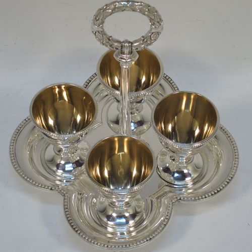 A very pretty Antique Victorian Sterling Silver egg cruet set, having four plain round egg cups with bead borders and gold-gild interiors sitting on pedestal feet, together with a cast laurel leaf loop handle attached to a lobed base with an applied bead-edged border, and all sitting on four cast claw and ball feet. Made by Elkington and Co., of Birmingham in 1866. The dimensions of this fine hand-made antique silver egg cruet set are height 18 cms (7 inches), width of base is 16.5 cms (6.5 inches), and the total weight is approx. 500g (16 troy ounces).