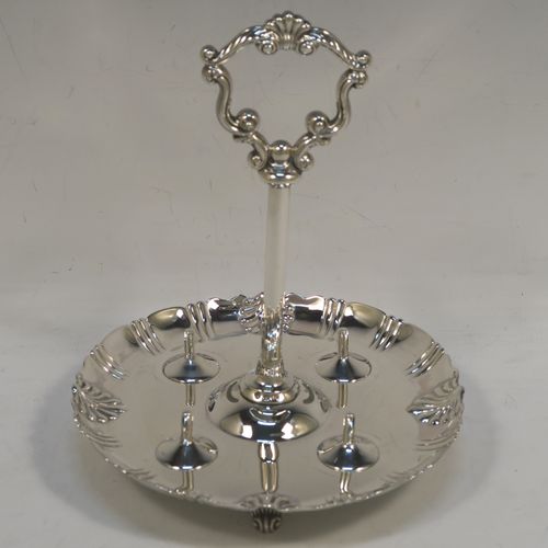 A very pretty Antique Victorian Sterling Silver egg cruet set with hand-chased fluted and shell decoration, having egg cups with gold-gilt interiors, and a cast shell and scroll loop handle attached to a round base sitting on four cast scrolled feet. This beautiful antique silver egg cruet set was made by Martin Hall and Co., of Sheffield in 1892 / 1898 (two of the egg cups are from 1892). The dimensions of this fine hand-made silver egg cruet set are height 18 cms (7 inches), the base is 15 cms (6 inches) in diameter, and the total weight is approx. 505g (16.3 troy ounces).