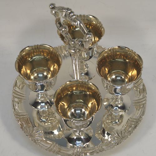 A very pretty Antique Victorian Sterling Silver egg cruet set with hand-chased fluted and shell decoration, having egg cups with gold-gilt interiors, and a cast shell and scroll loop handle attached to a round base sitting on four cast scrolled feet. This beautiful antique silver egg cruet set was made by Martin Hall and Co., of Sheffield in 1892 / 1898 (two of the egg cups are from 1892). The dimensions of this fine hand-made silver egg cruet set are height 18 cms (7 inches), the base is 15 cms (6 inches) in diameter, and the total weight is approx. 505g (16.3 troy ounces).