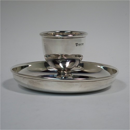 A Sterling Silver egg cup, having a plain round body with tapering sides, with an attached plain round plate with curved border, and sitting on a flat base. Made J. B. Chatterly of Birmingham in 1964. The dimensions of this fine hand-made silver egg cup are height 5 cms (2 inches), diameter 10 cms (4 inches), and it weighs approx. 87g (2.8 troy ounces).