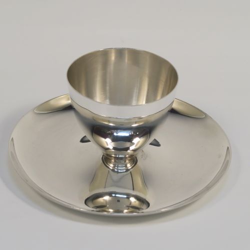 A Sterling Silver egg cup and plate, having a plain round body with tapering sides, with an attached plain round plate with curved border, and sitting on a flat base. This elegant silver egg cup was made by James Dixon Sons of Sheffield in 1943. The dimensions of this fine hand-made silver egg cup are height 4 cms (1.5 inches), diameter 9.5 cms (3.75 inches), and it weighs approx. 77g (2.5 troy ounces).