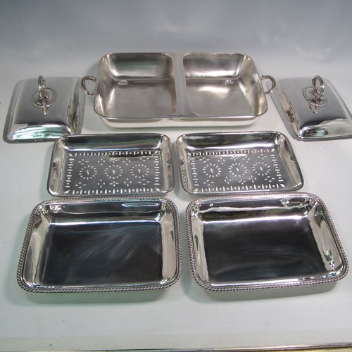 Sterling silver pair of entree dishes with covers and handles, sitting in an original plain rectangular hot-water warming frame, with applied gadroon borders and hand-pierced liners, having cast side-handles, and all sitting on four cushion feet. Made by D. & J. Wellby of London in 1916. The dimensions of this fine hand-made silver entree dish set are length 36 cms (14 inches), width 20 cms (8 inches), height including cover handles 12 cms (4.75 inches), and it weighs a total of approx. 1,965g (63 troy ounces).