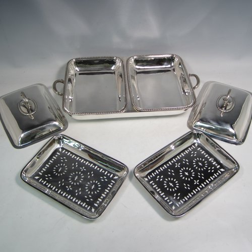 Sterling silver pair of entree dishes with covers and handles, sitting in an original plain rectangular hot-water warming frame, with applied gadroon borders and hand-pierced liners, having cast side-handles, and all sitting on four cushion feet. Made by D. & J. Wellby of London in 1916. The dimensions of this fine hand-made silver entree dish set are length 36 cms (14 inches), width 20 cms (8 inches), height including cover handles 12 cms (4.75 inches), and it weighs a total of approx. 1,965g (63 troy ounces).
