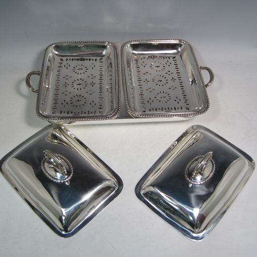 Sterling silver pair of entree dishes with covers and handles, sitting in an original plain rectangular hot-water warming frame, with applied gadroon borders and hand-pierced liners, having cast side-handles, and all sitting on four cushion feet. Made by D. & J. Wellby of London in 1916. The dimensions of this fine hand-made silver entree dish set are length 36 cms (14 inches), width 20 cms (8 inches), height including cover handles 12 cms (4.75 inches), and it weighs a total of approx. 1,965g (63 troy ounces).