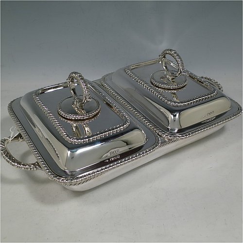 An Antique Edwardian Sterling Silver pair of entree dishes with covers on a silver-plated warming stand for hot water, having rectangular bodies with applied gadroon borders, and with removable bayonet-fit handles. All in original condition and made by Goldsmiths & Silversmiths of London in 1902. The dimensions of this fine pair of hand-made antique silver entree dishes on a silver plated warming stand are length (inc. handles) 34 cms (13.5 inches), width 20 cms (8 inches), height 12 cms (5 inches), and the entree dishes weigh approx. 1,721g (55.5 troy ounces).   