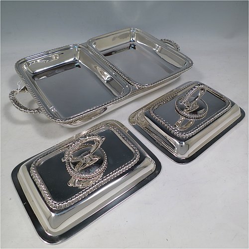 An Antique Edwardian Sterling Silver pair of entree dishes with covers on a silver-plated warming stand for hot water, having rectangular bodies with applied gadroon borders, and with removable bayonet-fit handles. All in original condition and made by Goldsmiths & Silversmiths of London in 1902. The dimensions of this fine pair of hand-made antique silver entree dishes on a silver plated warming stand are length (inc. handles) 34 cms (13.5 inches), width 20 cms (8 inches), height 12 cms (5 inches), and the entree dishes weigh approx. 1,721g (55.5 troy ounces).