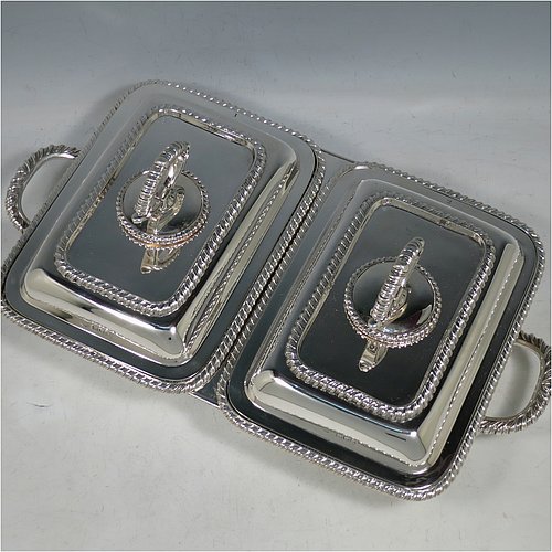 An Antique Edwardian Sterling Silver pair of entree dishes with covers on a silver-plated warming stand for hot water, having rectangular bodies with applied gadroon borders, and with removable bayonet-fit handles. All in original condition and made by Goldsmiths & Silversmiths of London in 1902. The dimensions of this fine pair of hand-made antique silver entree dishes on a silver plated warming stand are length (inc. handles) 34 cms (13.5 inches), width 20 cms (8 inches), height 12 cms (5 inches), and the entree dishes weigh approx. 1,721g (55.5 troy ounces).