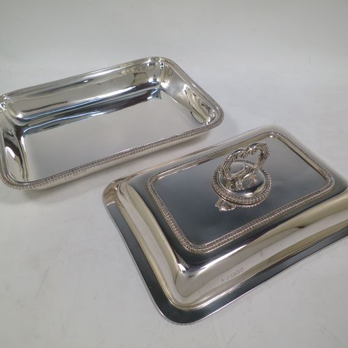 A handsome Antique Sterling Silver entree dish with cover, having a rectangular body with rounded corners and applied straight gadroon borders, a cast bayonet-fit removable asparagus style loop handle, and sitting on a flat base. Made by Carrington and Co., of London in 1912. The dimensions of this fine hand-made antique silver entree dish and cover are length 28 cms (11 inches), height including handle 11 cms (4.5 inches), width 20 cms (8 inches), and with a total weight of approx. 1,540g (49.7 troy ounces).