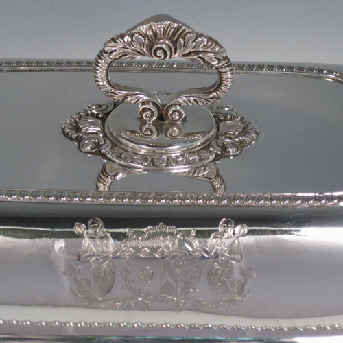Antique Georgian pair of entree dishes with covers, having rectangular bodies with rounded corners, bayonet-fit removable gadroon and shell handles, gadroon borders, and sitting on flat bases. Made by Joseph Angell of London in 1817. The dimensions of this pair of fine hand-made antique silver entree dishes and covers are length 29 cms (11.5 inches), height including handle 13 cms (5 inches), width 21.5 cms (8.5 inches), and they weigh a total of approx. 3,120g (101 troy ounces). Please note that these are crested, and the Latin motto has been translated as The Moon Shall Fill Her Horns Again.