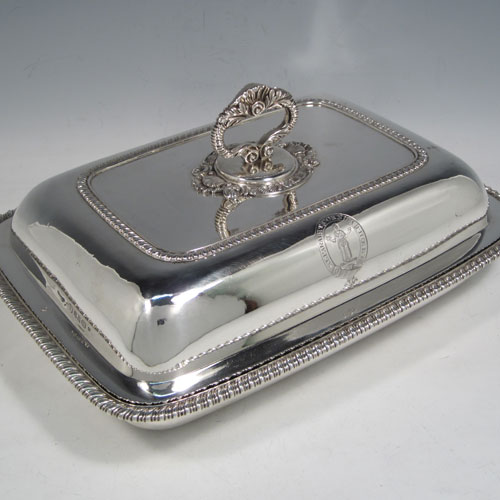 Antique Georgian pair of entree dishes with covers, having rectangular bodies with rounded corners, bayonet-fit removable gadroon and shell handles, gadroon borders, and sitting on flat bases. Made by Joseph Angell of London in 1817. The dimensions of this pair of fine hand-made antique silver entree dishes and covers are length 29 cms (11.5 inches), height including handle 13 cms (5 inches), width 21.5 cms (8.5 inches), and they weigh a total of approx. 3,120g (101 troy ounces). Please note that these are crested, and the Latin motto has been translated as The Moon Shall Fill Her Horns Again.