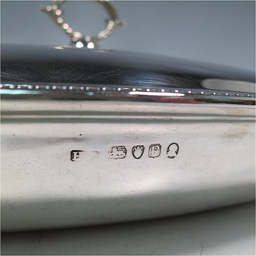 An Antique Georgian Sterling Silver pair of entree or hash dishes with covers, having oval bodies with applied bead-edged borders and cast loop side-handles, with plain domed lift-off covers having removable cast bead handles, and all sitting on flat bases. Made by Henry Green of London in 1790. The dimensions of this pair of fine hand-made antique silver entree dishes and covers are length 38 cms (15 inches), width 21.5 cms (8.5 inches), height including cover handle 11 cms (4.3 inches), and they weigh a total of approx. 2,077g (67 troy ounces). Please note that both the bases and covers are crested.