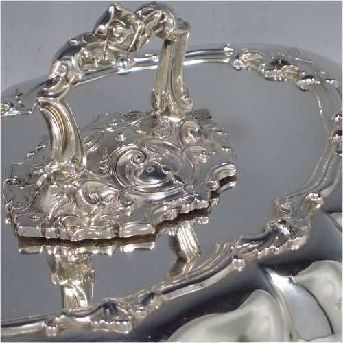 A very handsome Antique Sterling Silver pair of entree dishes, having oval lobed bodies, with lift-off lids, removable bayonet-fit handles, applied cast floral and scroll borders, and sitting on flat bases. These elegant silver entree dishes and covers were made by James Dixon & Sons of Sheffield in 1918. The dimensions of this fine pair of hand-made antique silver entree dishes and covers are length 35 cms (13.75 inches), width 26 cms (10.25 inches), and they weigh a total of approx. 3,472g (112 troy ounces).