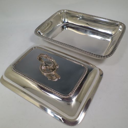 A handsome pair of Antique Georgian Sterling Silver entree dishes with covers, having rectangular bodies with rounded corners and applied gadroon borders, cast bayonet-fit removable asparagus style loop handles, and sitting on flat bases. Made by Richard Crossley of London in 1811. The dimensions of this pair of fine hand-made antique silver entree dishes and covers are length 29 cms (11.5 inches), height including handle 14 cms (5.5 inches), width 21 cms (8.25 inches), and they weigh a total of approx. 2,808g (90 troy ounces).