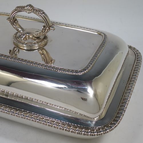 A handsome pair of Antique Georgian Sterling Silver entree dishes with covers, having rectangular bodies with rounded corners and applied gadroon borders, cast bayonet-fit removable asparagus style loop handles, and sitting on flat bases. Made by Richard Crossley of London in 1811. The dimensions of this pair of fine hand-made antique silver entree dishes and covers are length 29 cms (11.5 inches), height including handle 14 cms (5.5 inches), width 21 cms (8.25 inches), and they weigh a total of approx. 2,808g (90 troy ounces).