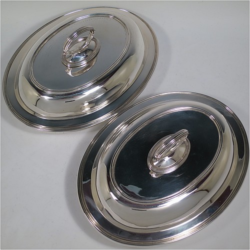 An Antique Victorian Sterling Silver pair of entree dishes, having plain oval bodies, with lift-off lids, removable bayonet-fit handles, applied reeded borders, and sitting on flat bases. Made by the Savory Brothers of London in 1893. The dimensions of this fine pair of hand-made antique silver entree dishes and covers are length 29 cms (11.5 inches), width 22 cms (8.75 inches), and they weigh a total of approx. 3,472g (112 troy ounces).