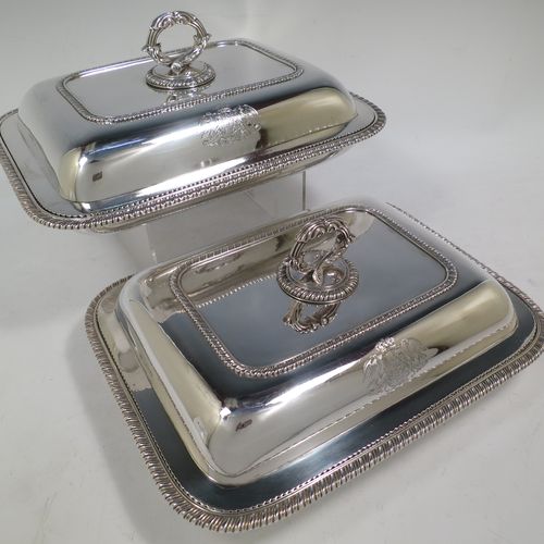 A very handsome and heavy pair of Antique Georgian Sterling Silver entree dishes with covers, having rectangular bodies with rounded corners and applied gadroon borders, cast screw-fit removable asparagus style loop handles, and sitting on flat bases. Made by Robert Garrard of London in 1803. The dimensions of this pair of fine hand-made antique silver entree dishes and covers are length 28.5 cms (11.25 inches), height including handle 12 cms (4.75 inches), width 22 cms (8.75 inches), and they weigh a total of approx. 3,220g (104 troy ounces). Please note that these items are crested.  