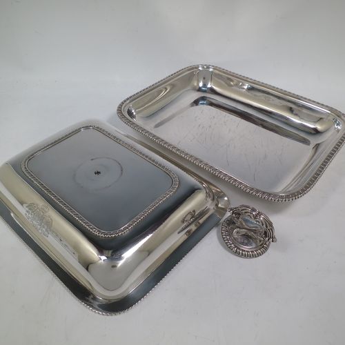 A very handsome and heavy pair of Antique Georgian Sterling Silver entree dishes with covers, having rectangular bodies with rounded corners and applied gadroon borders, cast screw-fit removable asparagus style loop handles, and sitting on flat bases. Made by Robert Garrard of London in 1803. The dimensions of this pair of fine hand-made antique silver entree dishes and covers are length 28.5 cms (11.25 inches), height including handle 12 cms (4.75 inches), width 22 cms (8.75 inches), and they weigh a total of approx. 3,220g (104 troy ounces). Please note that these items are crested.