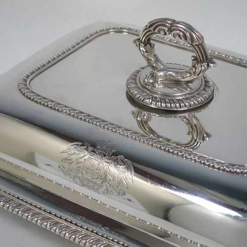 A very handsome and heavy pair of Antique Georgian Sterling Silver entree dishes with covers, having rectangular bodies with rounded corners and applied gadroon borders, cast screw-fit removable asparagus style loop handles, and sitting on flat bases. Made by Robert Garrard of London in 1803. The dimensions of this pair of fine hand-made antique silver entree dishes and covers are length 28.5 cms (11.25 inches), height including handle 12 cms (4.75 inches), width 22 cms (8.75 inches), and they weigh a total of approx. 3,220g (104 troy ounces). Please note that these items are crested.