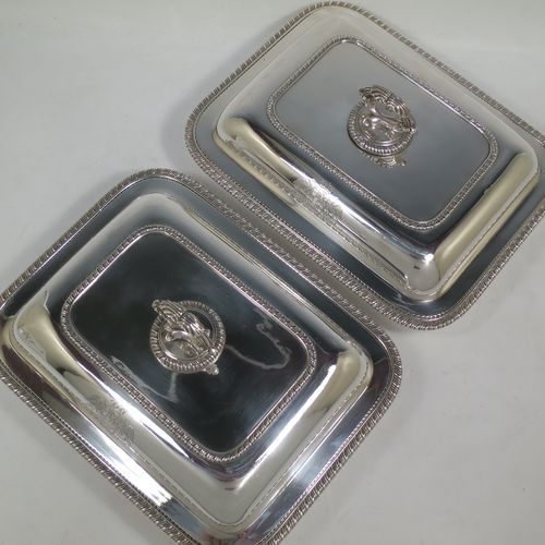 A very handsome and heavy pair of Antique Georgian Sterling Silver entree dishes with covers, having rectangular bodies with rounded corners and applied gadroon borders, cast screw-fit removable asparagus style loop handles, and sitting on flat bases. Made by Robert Garrard of London in 1803. The dimensions of this pair of fine hand-made antique silver entree dishes and covers are length 28.5 cms (11.25 inches), height including handle 12 cms (4.75 inches), width 22 cms (8.75 inches), and they weigh a total of approx. 3,220g (104 troy ounces). Please note that these items are crested.