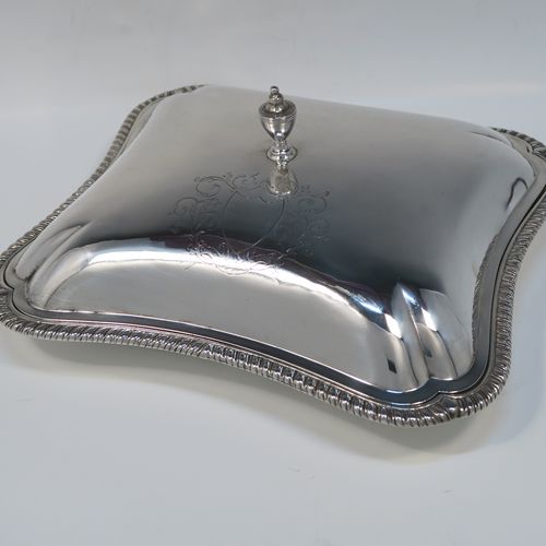 A very handsome pair of Irish Antique Georgian Sterling Silver entree or hash dishes with covers, having shaped rectangular bodies with applied gadroon borders, with plain domed lift-off covers and urn-shaped finials, and all sitting on flat bases. This elegant pair of antique silver entree dishes and covers were made by Thomas Jones of Dublin in 1796. The dimensions of this pair of fine hand-made antique Irish silver hash dishes and covers are length 26 cms (10.25 inches), width 23 cms (9 inches), and they weigh a total of approx. 2,140g (69 troy ounces).
