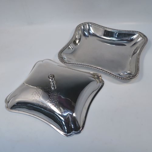 A very handsome pair of Irish Antique Georgian Sterling Silver entree or hash dishes with covers, having shaped rectangular bodies with applied gadroon borders, with plain domed lift-off covers and urn-shaped finials, and all sitting on flat bases. This elegant pair of antique silver entree dishes and covers were made by Thomas Jones of Dublin in 1796. The dimensions of this pair of fine hand-made antique Irish silver hash dishes and covers are length 26 cms (10.25 inches), width 23 cms (9 inches), and they weigh a total of approx. 2,140g (69 troy ounces).