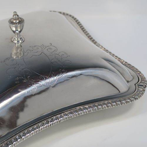 A very handsome pair of Irish Antique Georgian Sterling Silver entree or hash dishes with covers, having shaped rectangular bodies with applied gadroon borders, with plain domed lift-off covers and urn-shaped finials, and all sitting on flat bases. This elegant pair of antique silver entree dishes and covers were made by Thomas Jones of Dublin in 1796. The dimensions of this pair of fine hand-made antique Irish silver hash dishes and covers are length 26 cms (10.25 inches), width 23 cms (9 inches), and they weigh a total of approx. 2,140g (69 troy ounces).