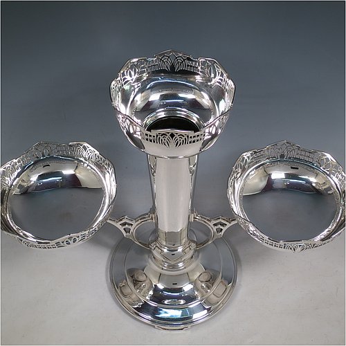 An Art Deco Sterling Silver table centrepiece or epergne, with hand-pierced geometrical style borders and Art Deco motifs, having one central flower vase, and two removable dishes resting on side arms, and all sitting on a pedestal base with four flanged feet. Made by James Dixon & Sons of Sheffield in 1934. The dimensions of this fine hand-made Art Deco style epergne or center-piece are height 33 cms (13 inches), width across arms 41 cms (16 inches), depth 16 cms (6.3 inches), and with a total weight of approx. 1,309 (42 troy ounces).   