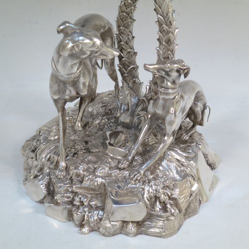 A very handsome Antique Victorian silver-plated table palm tree center-piece, having two palm trees inter-twined with a total of seven fronds, standing underneath which are two cast models of playful greyhounds or lurchers, and all sitting on a round naturalistic cast rock base. Made by Elkington and Co. with a date letter mark for 1852. The dimensions of this fine hand-made silver-plated table centerpiece display are height 41 cms (16 inches), spread across fronds 31 cms (12.25 inches), and diameter at base 20 cms (8 inches).

  