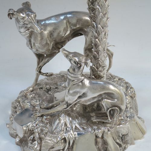 A very handsome Antique Victorian silver-plated table palm tree center-piece, having two palm trees inter-twined with a total of seven fronds, standing underneath which are two cast models of playful greyhounds or lurchers, and all sitting on a round naturalistic cast rock base. Made by Elkington and Co. with a date letter mark for 1852. The dimensions of this fine hand-made silver-plated table centerpiece display are height 41 cms (16 inches), spread across fronds 31 cms (12.25 inches), and diameter at base 20 cms (8 inches).

  