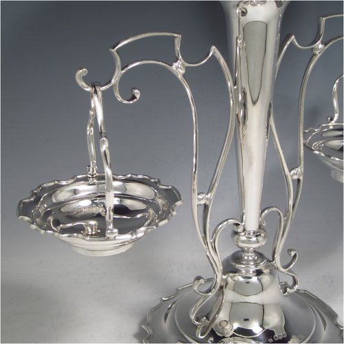 A Sterling Silver table Epergne centrepiece, having a removable central bowl, with two removable dishes on side arms, with applied scroll borders, an Art Nouveau style frame, and sitting on a spreading round base with four cushion feet. Made by the Deakin Brothers of Sheffield in 1924. The dimensions of this fine hand-made silver Epergne table centrepiece are height 32.5 cms (12.75 inches), width across arms 32 cms (12.5 inches), and it weighs a total of approx. 1,166g (37.6 troy ounces)   