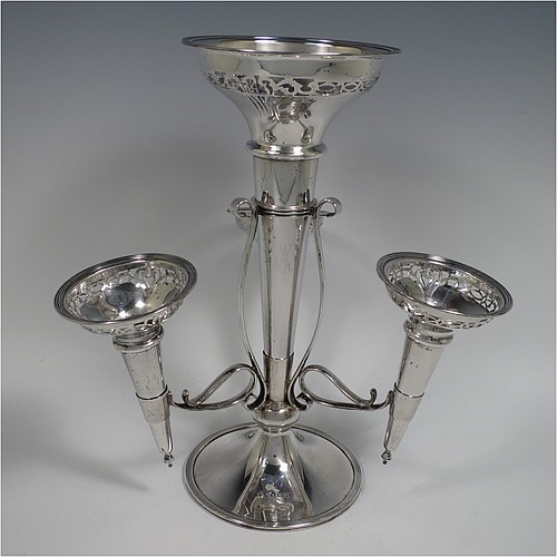 A Sterling Silver flower vase epergne center-piece, having four removable flower vases with hand-pierced top borders, with a central larger vase and three smaller side vases, all sitting on a pedestal base with wire-work scroll holders and applied reed-edged borders. Made by Henry Matthews of Birmingham in 1922. The dimensions of this fine hand-made sterling silver flower epergne are height 28 cms (11 inches), spread across vases 24 cms (9.5 inches), and it weighs approx. 645g (21 troy ounces).    