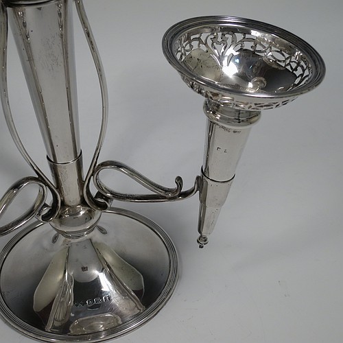 A Sterling Silver flower vase epergne center-piece, having four removable flower vases with hand-pierced top borders, with a central larger vase and three smaller side vases, all sitting on a pedestal base with wire-work scroll holders and applied reed-edged borders. Made by Henry Matthews of Birmingham in 1922. The dimensions of this fine hand-made sterling silver flower epergne are height 28 cms (11 inches), spread across vases 24 cms (9.5 inches), and it weighs approx. 645g (21 troy ounces).